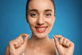 Young woman flossing her teeth on blue background. Cosmetic dentistry Royalty Free Stock Photo