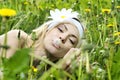 Young woman with flower in her hair blowing on a dandelion. Royalty Free Stock Photo