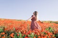 Young woman at a flowered poppy field. Woman in red dress with wild flowers Royalty Free Stock Photo