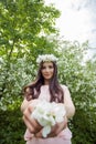 Young woman in flowers wreath in spring blossom park outdoors. Beautiful girl outdoor portrait on foliage background Royalty Free Stock Photo