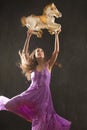 Young woman in purple dress dancing with antique carousel horse. Royalty Free Stock Photo