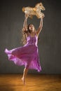 Young woman in purple dress dancing with antique carousel horse. Royalty Free Stock Photo