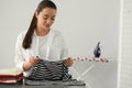 Young woman folding clothes at grey table indoors