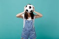 Young woman football fan cheer up support favorite team covering face with soccer ball isolated on blue turquoise wall Royalty Free Stock Photo