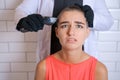 Young woman is forcibly shaving her head with an electric razor, holding Royalty Free Stock Photo