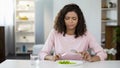 Young woman forcing herself to eat salad, dissatisfaction, weight control diet