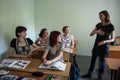 Young woman foreign language teacher in a small classroom gives students a lesson. In the