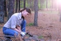 Young woman in forest camping cuts trunk of tree with an axe for firewood.