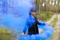 Young woman in forest having fun with blue smoke grenade, bomb Royalty Free Stock Photo