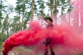 Young woman in forest having fun with red smoke grenade, bomb. Royalty Free Stock Photo