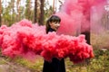 Young woman in forest having fun with red smoke grenade, bomb Royalty Free Stock Photo