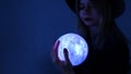 A young woman fortune teller in a hat is holding a magic ball. Royalty Free Stock Photo