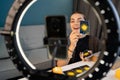 Young woman fortune teller recording video for blog using tarot cards, smartphone and ring lamp, predicts future online Royalty Free Stock Photo