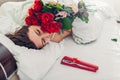 Young woman found bouquet of roses with jewellery in gift box in bed. Happy girl smelling flowers. Valentines day Royalty Free Stock Photo