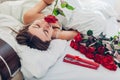 Young woman found bouquet of roses with jewellery in gift box in bed. Happy girl smelling flowers. Valentines day Royalty Free Stock Photo