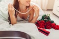 Young woman found bouquet of roses with jewellery in gift box in bed. Happy girl trying necklace on. Valentines day Royalty Free Stock Photo