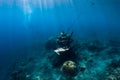 Young woman free diver glides with fins near underwater temple. Freediving in blue ocean