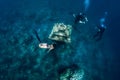 Young woman free diver glides with fins near underwater temple. Freediving in blue ocean