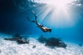 Young woman freediver glides over sandy sea with fins. Freediving in clear ocean and sun light