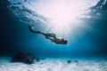 Young woman freediver glides over sandy sea with fins. Freediving in clear ocean and sun light