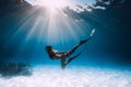 Young woman freediver glides over sandy sea