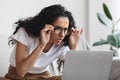 Young woman with bad eyesight using laptop, wearing glasses Royalty Free Stock Photo