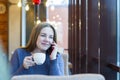 Young woman freelancer enjoying coffee during cellular conversation in cafe interior Royalty Free Stock Photo