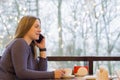 Young woman freelancer enjoying coffee during cellular conversation in cafe interior Royalty Free Stock Photo