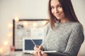 Young woman freelancer indoors home office concept winter atmosphere blurred background writing in planner smiling Royalty Free Stock Photo