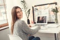 Young woman freelancer indoors home office concept winter atmosphere sitting writing in planner smiling