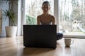 Young woman, freelancer, sitting on her living room floor working on laptop computer Royalty Free Stock Photo