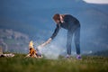 Young woman freelancer throws firewood into a fire in the mountains in the evening. tourist girl Royalty Free Stock Photo