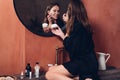 Young woman in front of the mirror putting cream on her face Royalty Free Stock Photo
