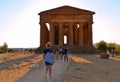 20.08.2018. Young woman in front of Ruined Temple Concordia on hill and tourists in famous ancient Valley of Temples, Agrigento, S