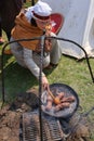 Young woman frying black sausage on the campfire at Rekawka - a pagan folk festival