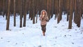 A young woman in a fur coat runs away from a pursuer in a winter forest