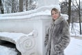 A young woman in a fur coat stands near a half-round in a winter park