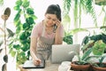 Young woman gardener is standing in the garden to contact customers.