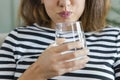 Young woman gargling with a glass of water