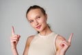 Young Woman Gesturing With One Finger Up Against a Grey Backdrop