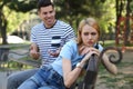 Young woman getting bored during date with overtalkative man in park Royalty Free Stock Photo