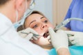 Young woman getting dental treatment closeup, hands of dentist and assistant makes treatment procedures to female Royalty Free Stock Photo