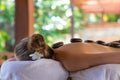 Young woman getting hot stone massage in spa salon. Beauty treat Royalty Free Stock Photo