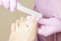 Young woman getting professional pedicure in a beauty salon, closeup. Hands a pedicurist in protective rubber gloves are applied w