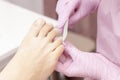 Young woman getting professional pedicure in a beauty salon, closeup. Hands a pedicurist in protective rubber gloves are applied w