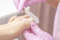 Young woman getting professional pedicure in a beauty salon, closeup. Hands a pedicurist in protective rubber gloves are applied w