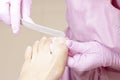 Young woman getting professional pedicure in a beauty salon, closeup. Hands a pedicurist in protective rubber gloves are applied w