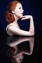 Young woman with ginger hair over reflection mirror on blue back Royalty Free Stock Photo