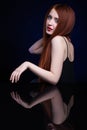 Young woman with ginger hair over reflection mirror on blue back Royalty Free Stock Photo