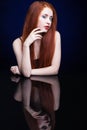 Young woman with ginger hair over reflection mirror on blue back Royalty Free Stock Photo